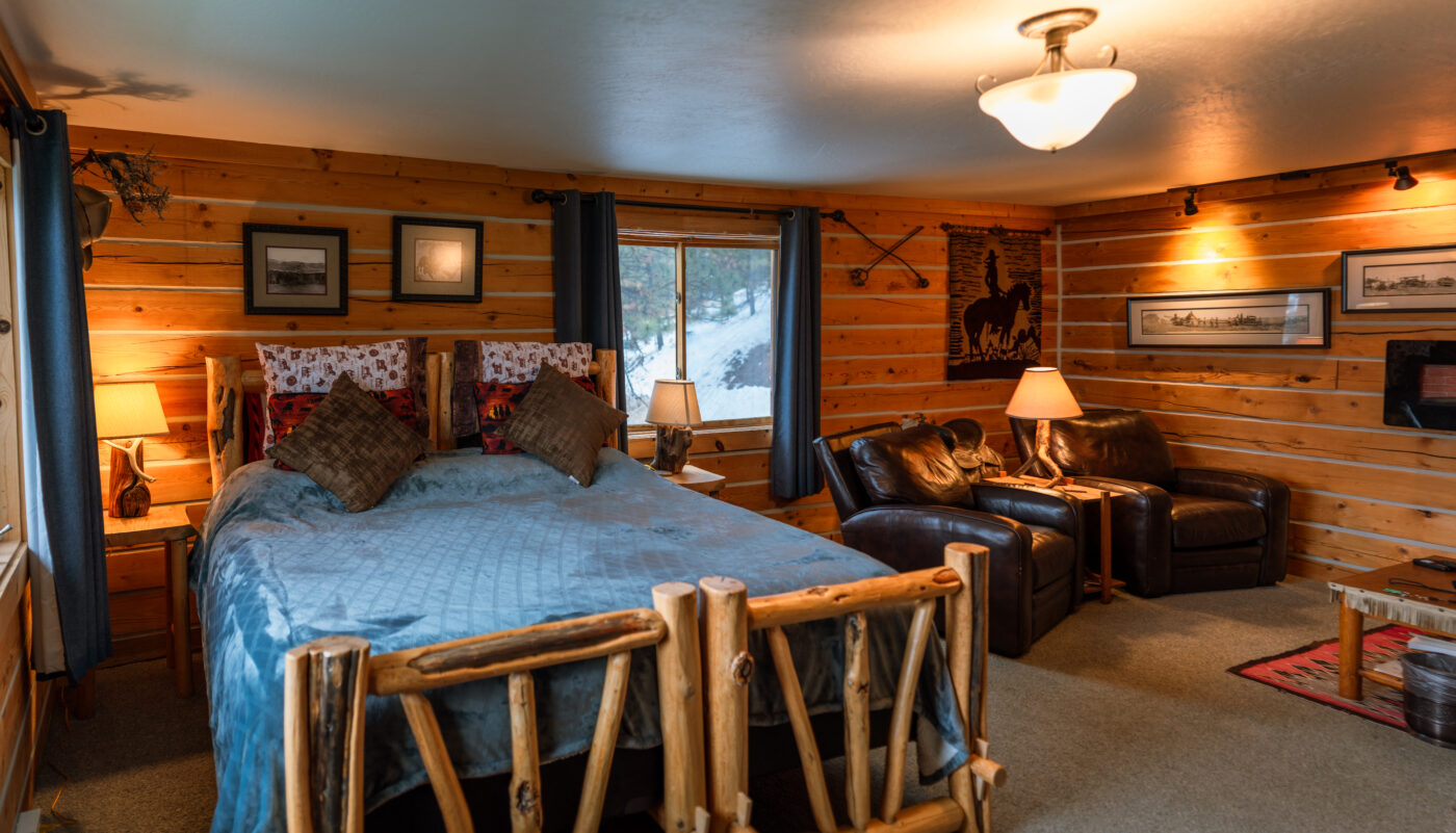 Room with bed, log cabin walls, and sitting area with leather chairs at our Missoula Bed and Breakfast