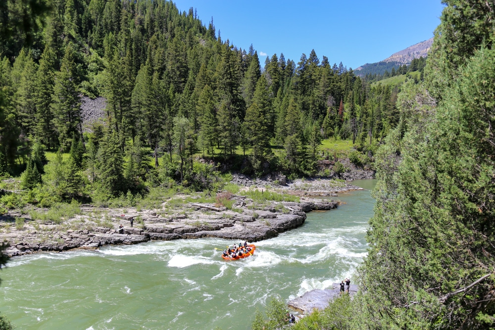A group whitewater rafting through a river canyon, similar to what you'd experience whitewater rafting on the Alberton Gorge near Missoula