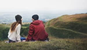 Plan the best Montana Getaway in Missoula. A couple sits atop a mountain talking to each other.